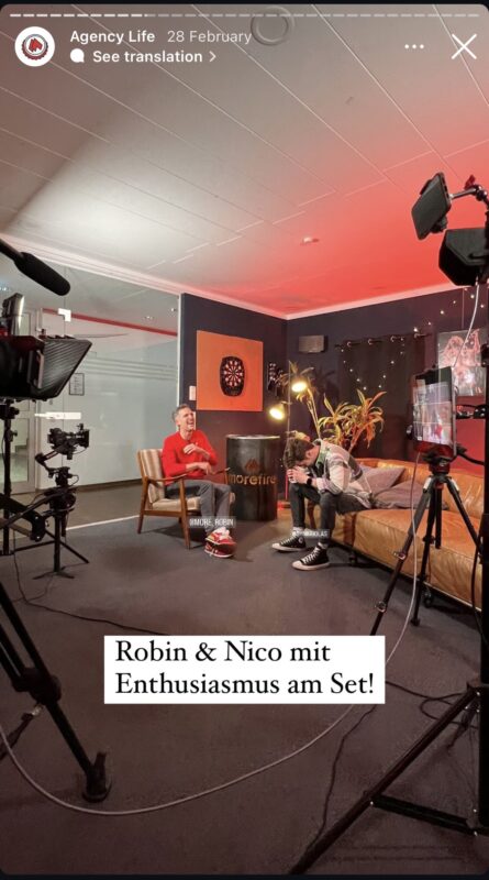 Robin und Nico bei einem Dreh im morefire Set, voller Enthusiasmus in einem gemütlichen Studio mit Kameras und Beleuchtung